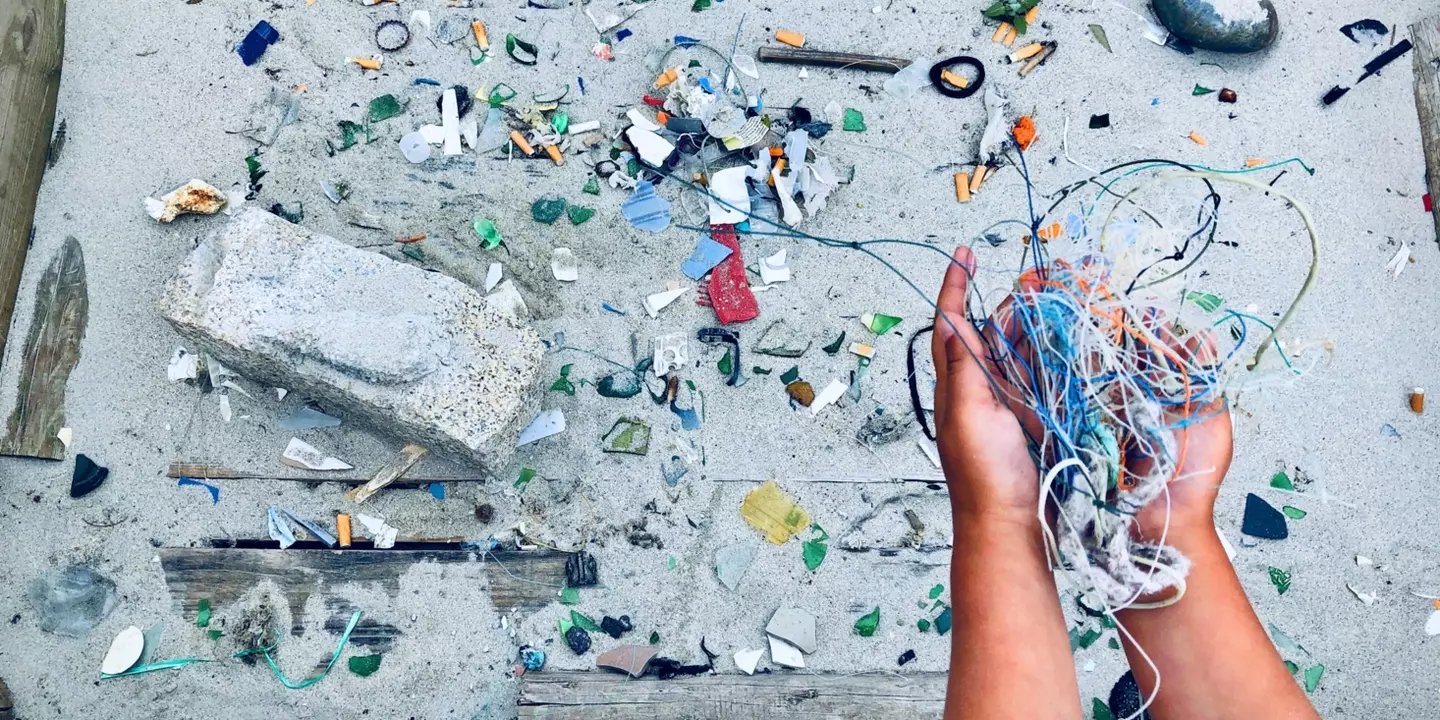 Enfant tenant des déchets plastique dans ses mains sur la plage.