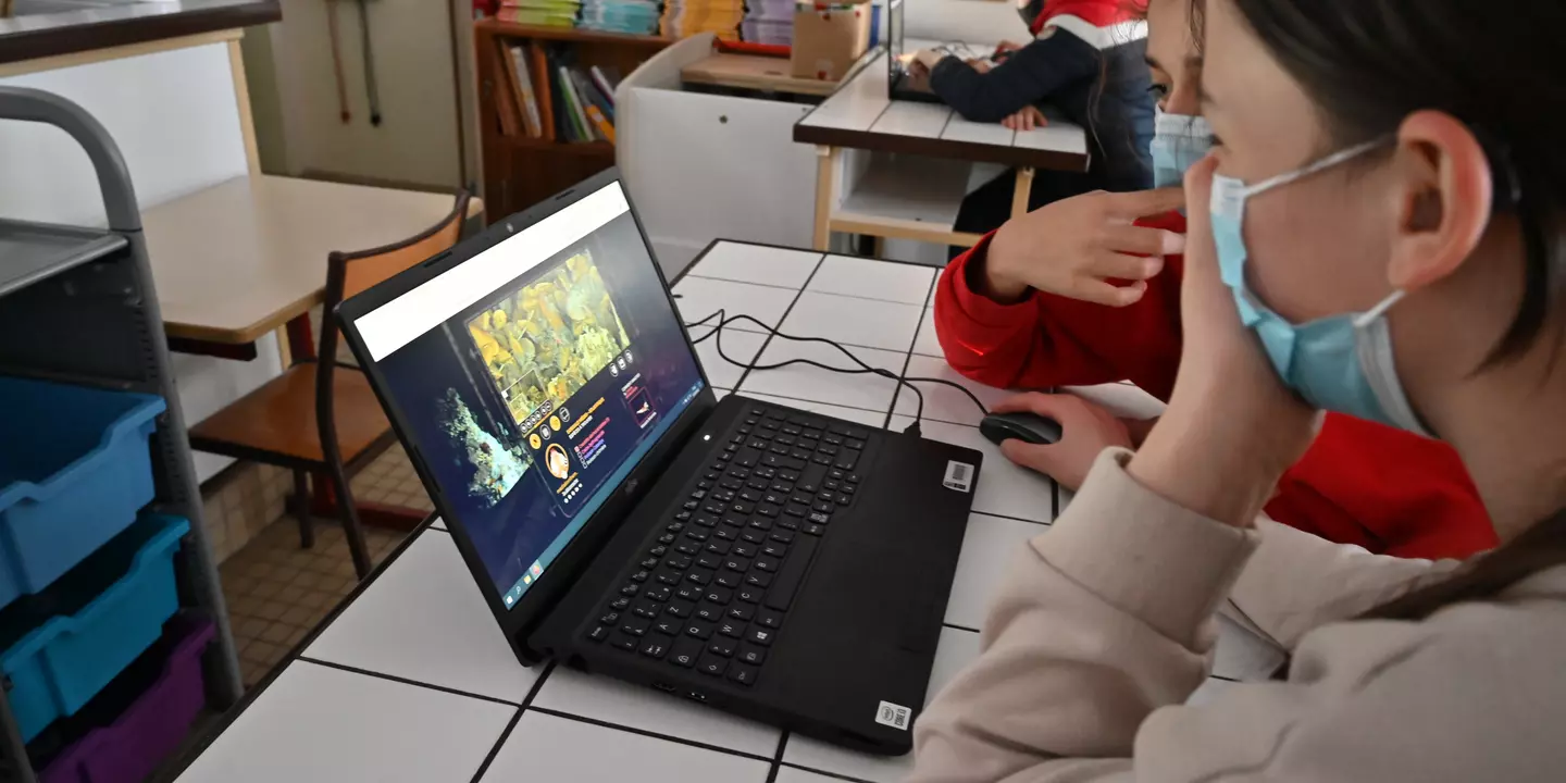 Élèves devant un ordinateur dans une salle de classe.