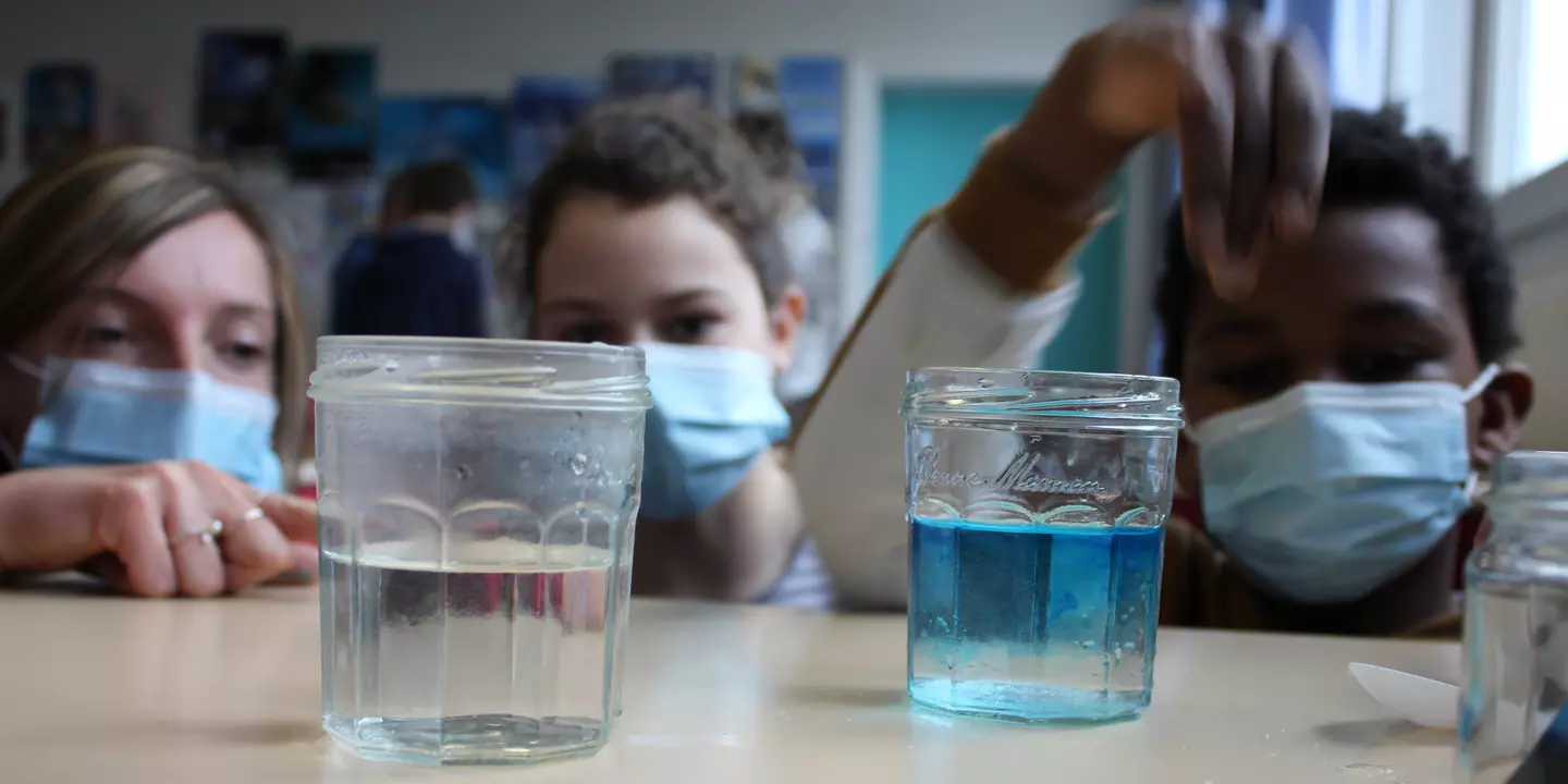 Personne expliquant une expérience à des élèves en classe.