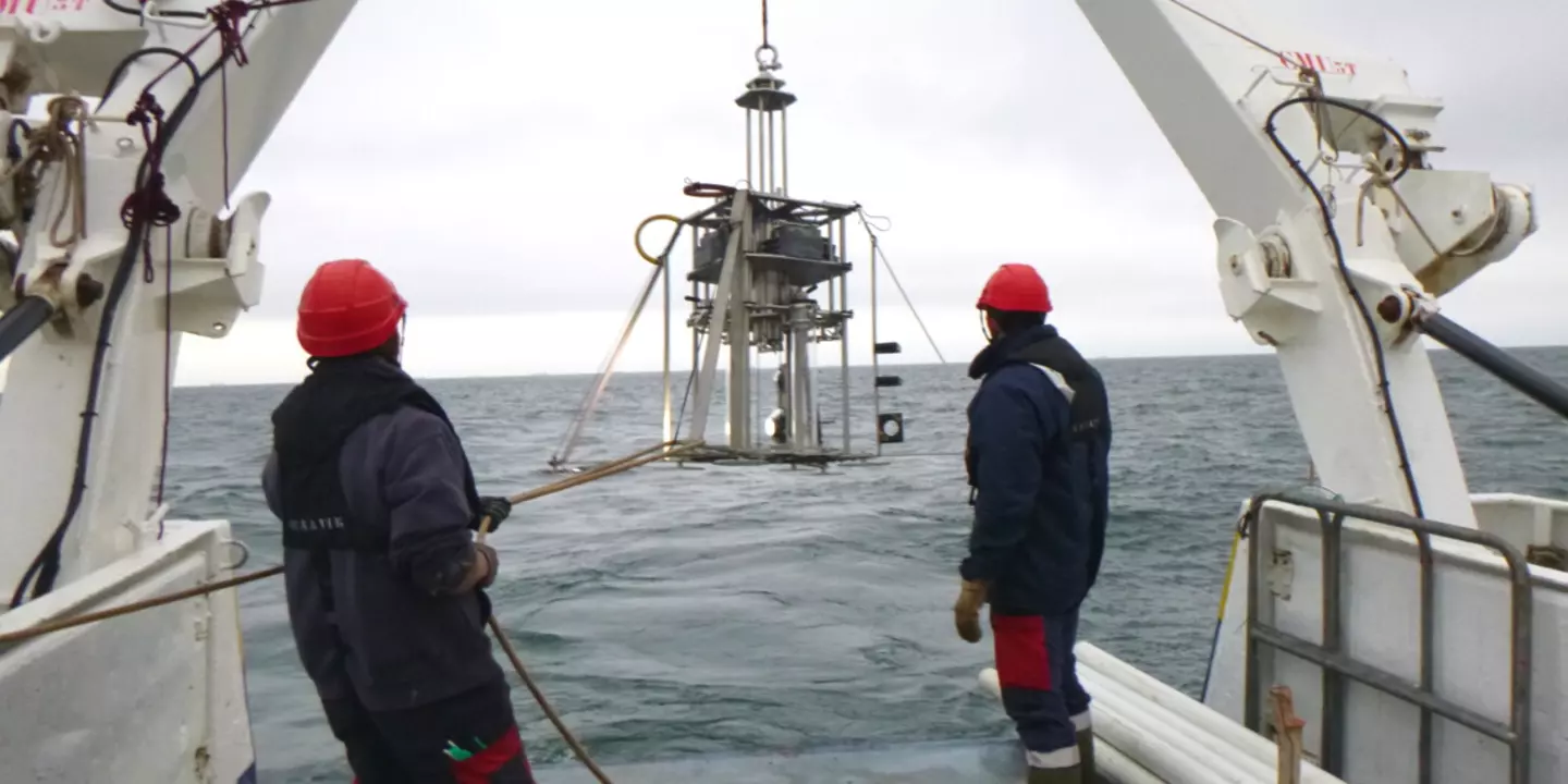 Deux personnes en train de manipuler un engin sur la poupe du bateau.