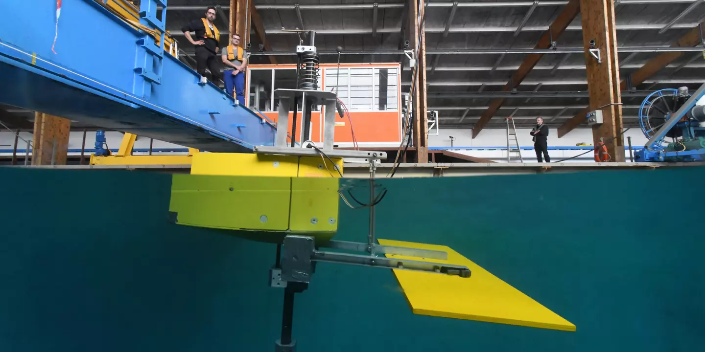 Vue sur le côté d'un prototype de système houlomoteur placé dans un bassin d'essais.