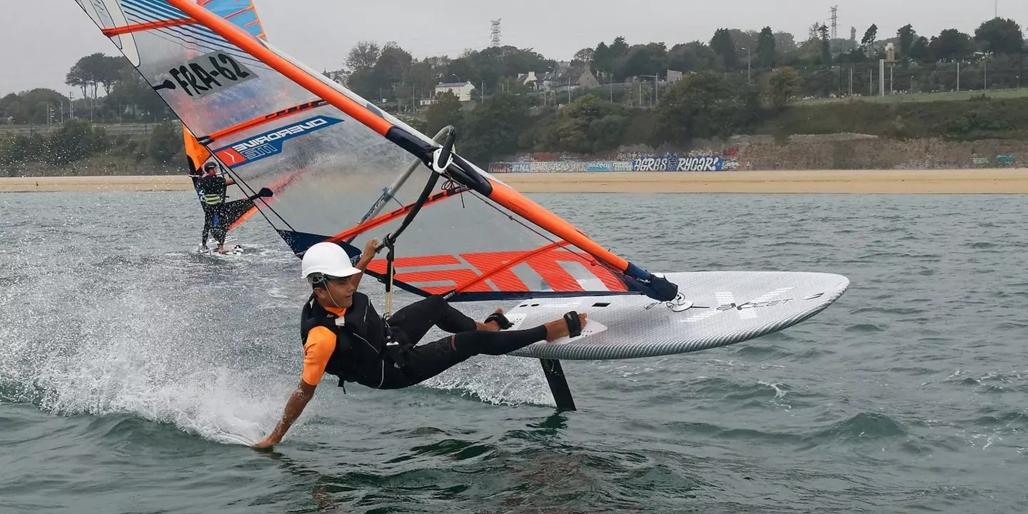 Un planchiste, sa planche à voile et son foil dans la rade de Brest