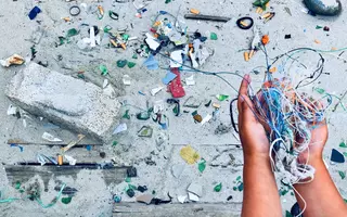 Enfant tenant des déchets plastique dans ses mains sur la plage.