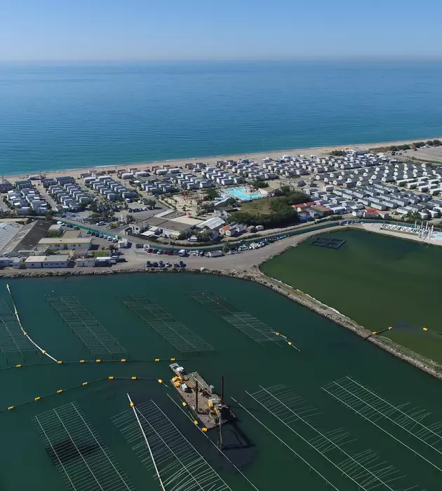 Vue du ciel d'une plateforme en bord de mer composée de plusieurs bâtiments sur la côte et d'équipements en mer