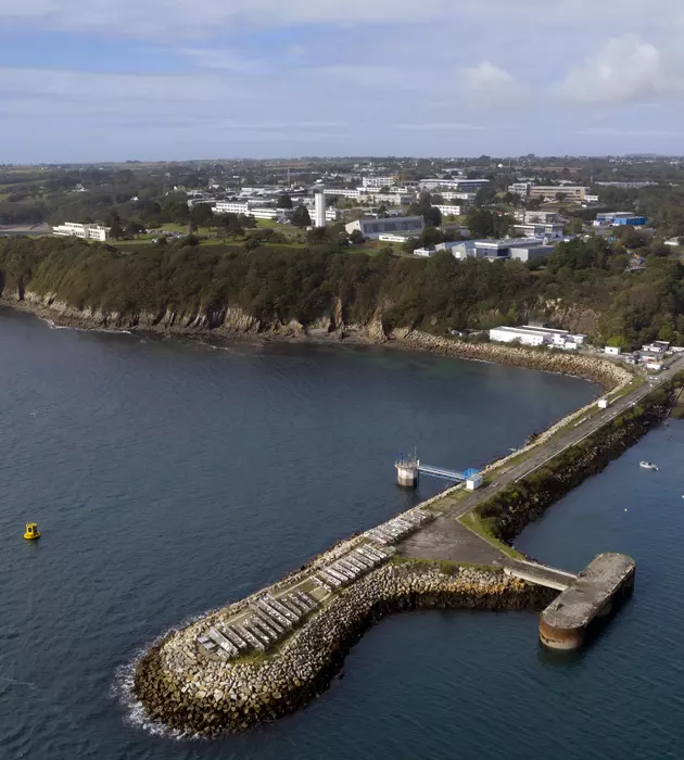 Vue aérienne du site de Brest, il y a une masse de bâtiments à quelques centaines de mètres de la côte et une avancées fine dans la mer