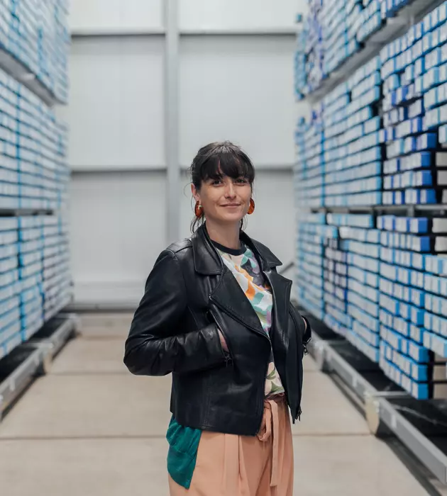 Femme dans une allée avec des éléments de stockages bleus de part et d'autres de l'allée.