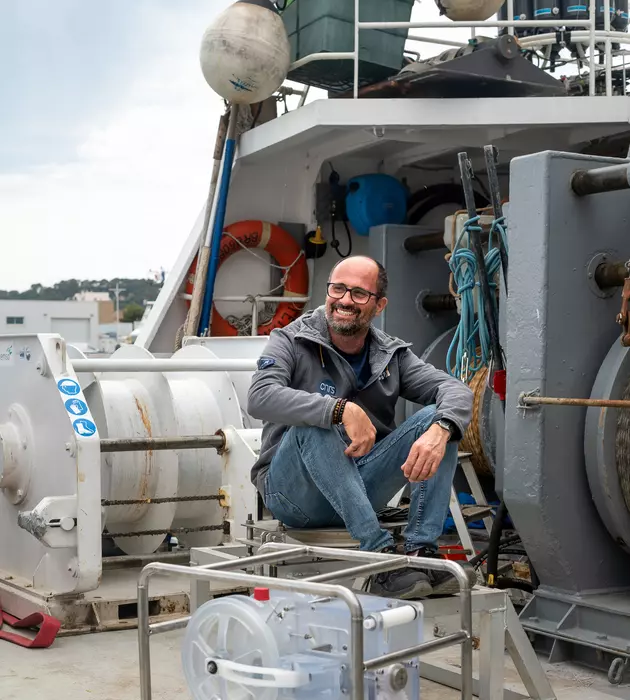 Homme assis sur des éléments d'un bateau.