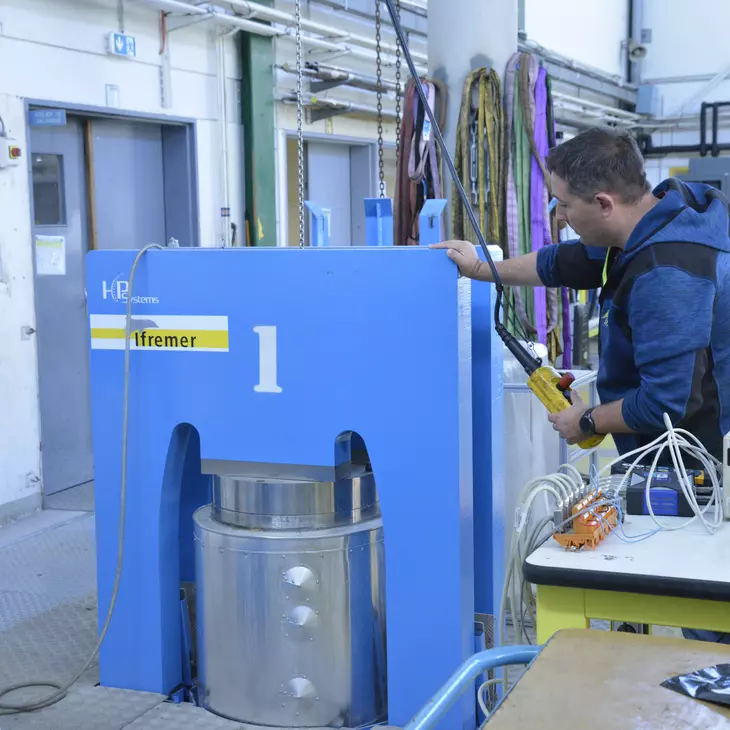 Personne devant un caisson cylindrique gris inséré dans un élément bleu