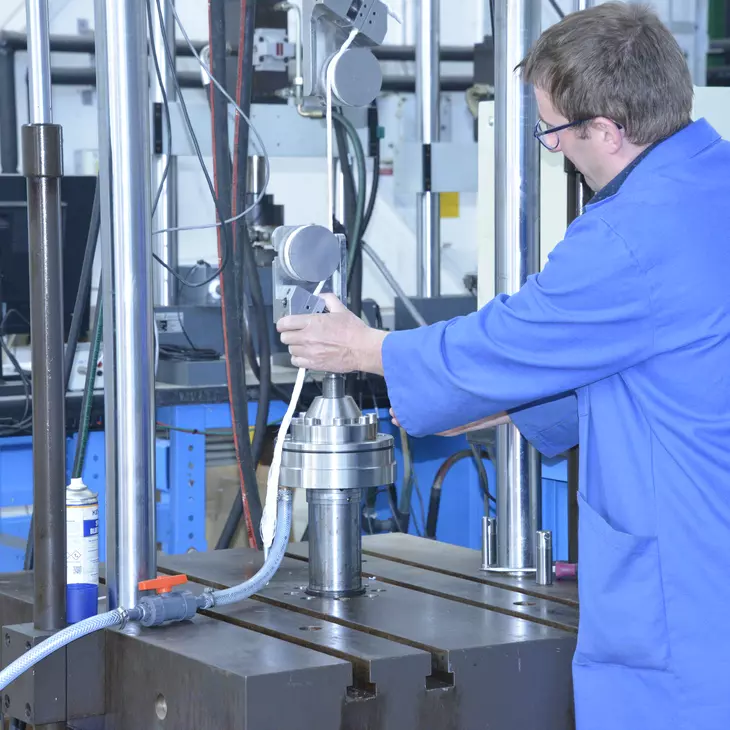 Une personne mettant en place un petit cylindre dans une machine hydraulique