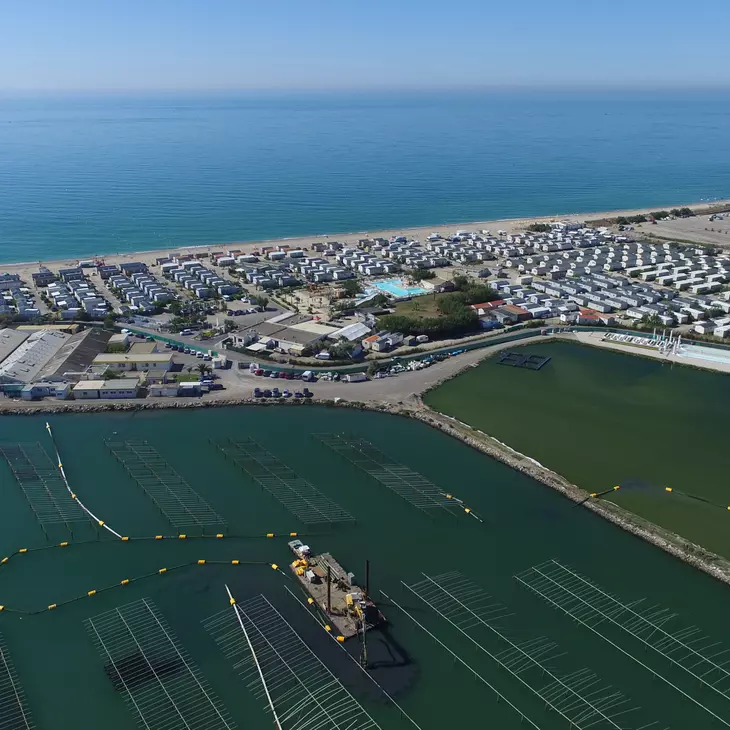 Vue du ciel d'une plateforme en bord de mer composée de plusieurs bâtiments sur la côte et d'équipements en mer