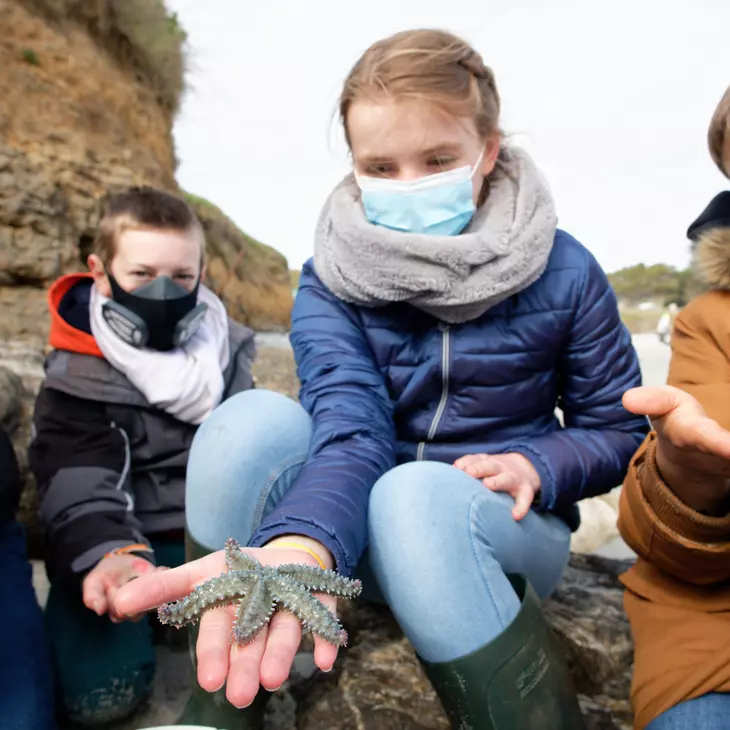 Enfant présentant une étoile de mer dans sa main droite