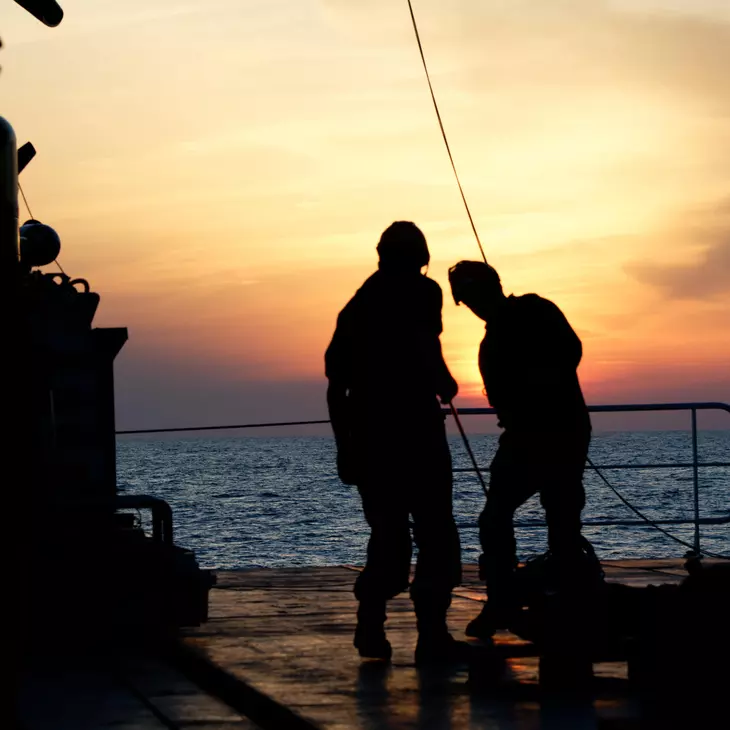 Deux personnes sur le bateau en contre jour d'un couché de soleil.